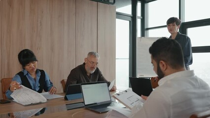 Wall Mural - Multinational team of colleagues gathered around table discussing project in office