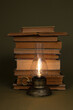 Old books and a lamp with a burning light on an olive background.