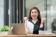 © Songsak C - Asian businesswoman showing clenched fist, smiling, feeling happy with her project result