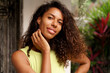 © Svetlana Sokolova - A close-up portrait captures the cheerful smile of a beautiful African American woman with dark skin, wavy hair, and an enchanting face as she poses in a tropical villa during summer vacations.