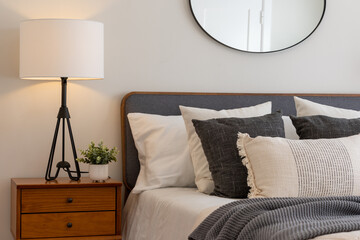 relaxing bedroom detail of bed with gray and white linen textured bedding, decorative wood side tabl