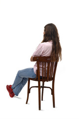 Wall Mural - back and side  view of a young girl sitting on chair with arms crossed on white background