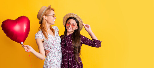 Mother and daughter kid banner, copy space, isolated background. positive mom and daughter hold love heart balloon on yellow background.