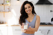 © Maria Vitkovska - Portrait of brunette cheerful fit woman holding glass of fresh milk