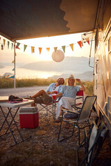 Wall Mural - Couple having fun outdoors.Cheerful  man and woman Partying Near Modern Camper Van In Camping