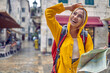 © luckybusiness - Walk in city in rain. Young tourist woman in raincoat with map, feeling happy, smiling. Travel in new city. Tourism, lifestyle, fun, weather concept.