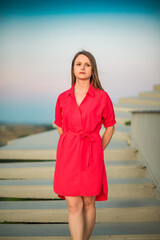 Wall Mural - Portrait of a young beautiful girl in a red dress outdoors in summer.