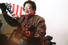 Senior Woman In Leather Jacket Riding Motorcycle And Waving  American Flag On White Background
