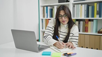 Poster - Young beautiful hispanic woman student using laptop taking notes at library university