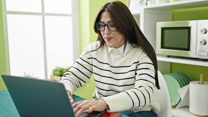 Poster - Young beautiful hispanic woman using laptop having idea at dinning room