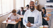 © K Louw/peopleimages.com - Portrait, black man and teacher in a class, students and smile with knowledge, education and development. Face, male person and educator with a test, exam or learning in a school, happiness or growth