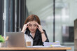 © Songsak C - Asian young businesswoman feeling stress and headache while working with laptop in the work office.