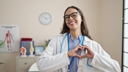 Sticker - Young beautiful hispanic woman doctor smiling doing heart gesture with hands at clinic