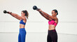 © Emil Lime/peopleimages.com - Woman, personal trainer and kettlebell in weightlifting for workout, exercise or fitness together outdoors. Women lifting kettle bells for exercising, strength or training body in health and wellness