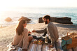 © Emil L/peopleimages.com - Picnic, beach and couple with champagne happy for relax, bonding and quality time on romantic date. Nature, dating and man and woman toast for anniversary, honeymoon and love on holiday or vacation