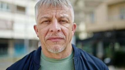 Wall Mural - Middle age grey-haired man standing with serious expression at street