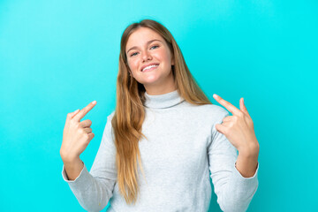 Wall Mural - Young blonde woman isolated on blue background giving a thumbs up gesture