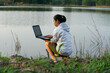 © Pornpimon - Female environmentalist using laptop computer to record natural water contamination checks. Biologist analyzing water test results using technology application on laptop. Water and ecology concept