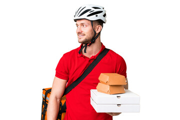 Wall Mural - Young delivery man taking a takeaway food over isolated chroma key background looking side