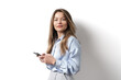 © arthurhidden - Young caucasian woman, professional entrepreneur standing in office clothing, smiling and holding a mobile phone on white background