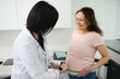© Taras Grebinets - Female doctor obstetrician gynecologist measures the height of the fundus of the uterus, the volume of the abdomen of a pregnant woman during a regular medical examination in a gynecological clinic
