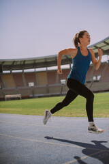 Wall Mural - Sporty girl running at the stadium