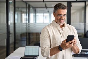 copy space are with smiling mature latin or indian businessman holding smartphone in office. middle 