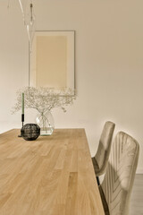 a vase with flowers on top of a wooden table next to two chairs and a mirror in the back wall