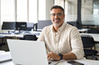 © Stock 4 You - Portrait of mature Indian or Latin business man ceo trader using laptop computer, typing, working in modern office. Middle-age Hispanic smiling handsome businessman entrepreneur looking at camera.