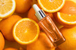 Cosmetic bottle product serum vitamin C with orange and lemon flat lay on yellow background, top view, copy space