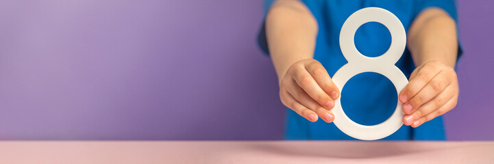 Fototapete - Number 8 in hand. A hand holds a white number eight on a purple background, eight percent per annum. The concept of international women's day on March 8. Advertising banner or greeting card.