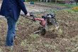 A farmer plows the land with a hand-held motor plow. Agricultural machinery: cultivator for tillage in the garden, motorized hand plow.