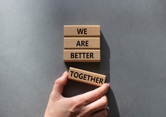 Wall Mural - We are stronger together symbol. Wooden blocks with words We are stronger together. Businessman hand. Beautiful grey background. We are stronger together concept. Copy space.