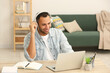 © New Africa - African American man in headphones working on laptop at wooden table in room
