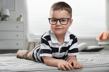 Cute little boy in glasses on floor at home