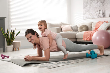 Wall Mural - Mother doing exercise with her daughter at home