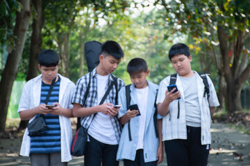 Blurred image of young asian boys are using mobile phone and walking homes afterschool together, soft and selective focus, concept for teen lifestyle and teenagers's spending times.