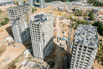 closeup aerial view of high-rise apartment buildings under construction and working cranes.