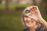 Fototapeta Pokój dzieciecy - View of crystal ball with upside down reflection of  smiling woman holding it; grass and trees in background