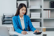 © Kritdanai - Asian Business woman using calculator and laptop for doing math finance on an office desk, tax, report, accounting, statistics, and analytical research concept