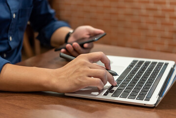 Wall Mural - Person hands typing on laptop keyboard at the office. Business man hands typing online learning, internet marketing, searching the information and technology concept.