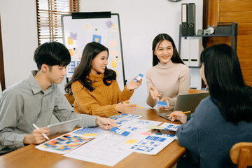  UX developer and ui designer brainstorming about mobile app interface wireframe design with customer breif and color code at office.