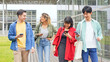 © metamorworks - Multinational youth group walking with smart phone in college campus. College students.