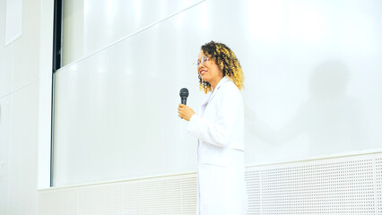 Female lecturer giving a lecture in the auditorium. University professor. Science student.