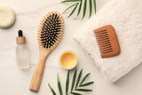 Flat lay composition with wooden hair brush and comb on white marble table