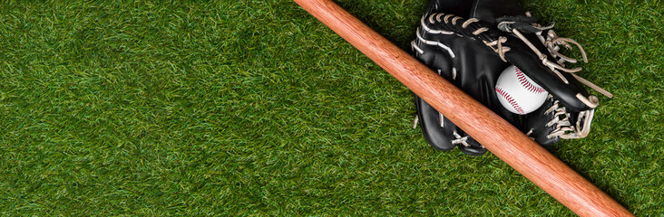 Canvas Print - Baseball bat, glove and ball on green grass field. Sport theme background with copy space for text and advertisment