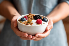 A person holding a bowl of cereal and berries. Generative AI.