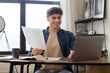 © Prostock-studio - Arabic Man Using Laptop Holding Papers Sitting At Desk Indoors