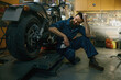 © Nomad_Soul - Satisfied smiling mechanic feeling glad looking at repaired motorcycle