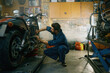 © Nomad_Soul - Young mechanic working on motorcycle in garage repair service